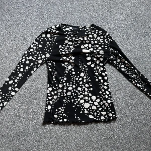 Svart långärmad topp med mönster - Säljer en svart långärmad topp från lindex. Toppen är ribbad och har en tight passform, perfekt att styla med jeans eller kjol för en cool look.