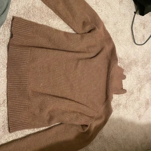 Brun polotröja från DAZY - Mysig brun polotröja från DAZY i storlek L. Tröjan är stickad med ribbade muddar och hög polokrage, perfekt för kyliga dagar. Enkel och stilren design som är lätt att matcha med olika outfits.