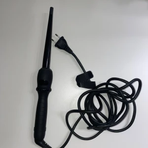 CeraWand Locktång - CeraWand locktång med digital temperaturdisplay, justerbar upp till 210°C. Ergonomiskt handtag och lång sladd med kardborreband för enkel förvaring. Produkten är i gott skick utan synligt slitage eller defekter, redo att användas för snygga lockar. Enda märket som passar för mitt tjocka hår.