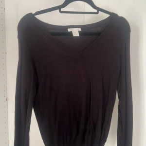 Svart v-ringad tröja från H&M - Svart långärmad tröja från H&M Basic i storlek XS. Tröjan har en snygg v-ringning och ribbad kant vid halsen. Perfekt att matcha med jeans eller kjol för en enkel och stilren look.
