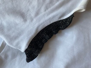 Vit topp med glittriga svarta volangärmar - Säljer en jätte fin vit topp med svarta guld-glitter volanger, knappt använd. Skriv om du är intresserad ❤️