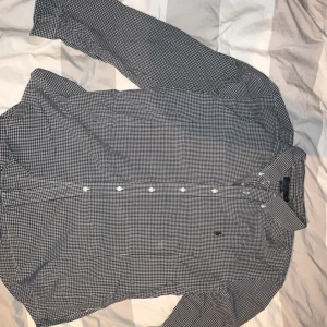 Svartvit rutig skjorta Polo Ralph Lauren - Storlek xxl men passar även XLSnygg svartvit rutig skjorta från Polo Ralph Lauren i slim fit-modell. Skjortan har klassisk krage, långa ärmar och knappar framtill. Tillverkad i mjuk bomull och har den ikoniska Polo-loggan broderad på bröstet. Perfekt för dig som gillar stilrena och tidlösa plagg.