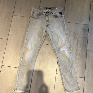 Replay ljusgrå jeans Thad - Snygga ljusgrå jeans från Replay, modell Thad. Storlek 28/30 Klassisk femficksdesign med Replay-logga på fickan. Jeansen har rak passform och är tillverkade i mjukt jeanstyg som ger en skön känsla. Perfekt för dig som gillar stilrena och moderna jeans.