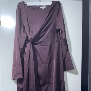 Vinröd omlottklänning från VILA - Supersnygg vinröd långärmad klänning från VILA med omlottdetalj och knyt i midjan. Klänningen har en elegant, enkel design och är tillverkad i ett slätt material som ger en lyxig känsla. Perfekt för dig som vill sticka ut med stil.