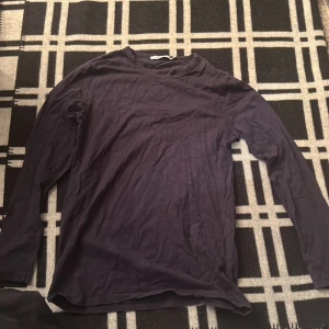 Mörkblå långärmad tröja Samsøe Samsøe - En stilren mörkblå långärmad tröja från Samsøe Samsøe i storlek M. Tröjan har en klassisk rund halsringning och är tillverkad i mjuk bomull, perfekt för lager-på-lager eller som den är. Enkel och clean design som funkar till det mesta.