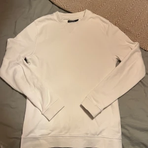 Vit sweatshirt från Dressmann M - Säljer en stilren vit sweatshirt från Dressmann i storlek M. Tröjan har rund hals, långa ärmar och ribbade muddar vid ärmslut och nederkant. Ny, endast använd 2-3 gånger 