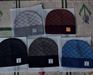 Louis Vuitton mössa - Snygga mössor från Louis Vuitton med klassiskt rutigt mönster och LV-logga framtill. Finns i grått, vinrött, svart, mörkgrått och blått. Mössorna har uppvikt kant och är tillverkade i mjukt stickat material som passar perfekt för kyliga dagar.
