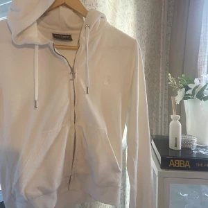 Vit hoodie från Juicy Couture - Säljer min fina vita zip-up hoodie från Juicy Couture i storlek S. Tröjan har huva med snörning, dragkedja framtill och en broderad JC-logga på bröstet. Mjuk och skön, ikonisk och klassisk velour. Stora fickor framtill och långa ärmar. Pris kan diskuteras🤍🤍