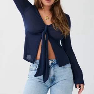 Mörkblå långärmad omlottopp med knyt - Snygg mörkblå omlottopp med lång ärm och knyt framtill som ger en croppad look. Tunn och mjuk kvalitet. Toppen har en djup v-ringning och är figurnära över armarna.