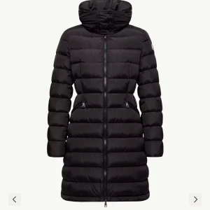 Svart lång dunjacka från Moncler - Säljer en svart, lång och quiltad dunjacka från Moncler med luva. Jackan har dragkedja framtill, två fickor med dragkedja och klassisk Moncler-logga på ärmen. Kan skicka egna bilder vid intresse. Har kvitto, klädöverdrag från moncle och påse kvar. Köpt på Biblioteksgatan i Stockholm