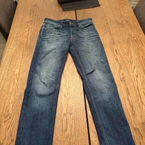 Blå jeans från Jack & Jones, 28/30 - Säljer ett par klassiska blå jeans från Jack & Jones i storlek 28/30. Jeansen har en snygg tvätt. Perfekta för dig som gillar en tidlös look och vill ha ett par jeans som funkar till det mesta.