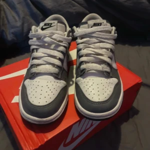 Nike Dunk Low i grått och vitt - Nike Dunk Low sneakers smokey grey. Super bra skick, inte använda mycket men finns slitage vid hälen inuti skon strl 37