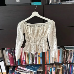 Vit spetsblus från H&M med volang - Superfin vit blus från H&M i storlek 158 (passar mig med ex), med långärmade ärmar och  offshoulder. 