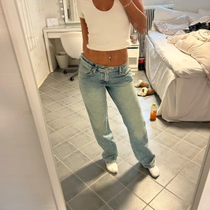 Ljusblå straight jeans från H&M - Säljer ett par ljusblå jeans från H&M i rak modell med låg midja. Jeansen har klassisk femficksdesign och regular fit, perfekta för en chill och avslappnad look. Materialet är mjukt denim och färgen är snyggt tvättad för en vintage vibe.
