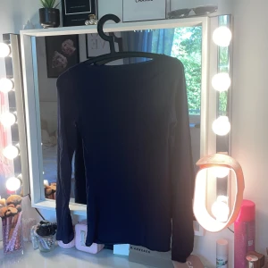 Mörkblå långärmad topp - Snygg mörkblå långärmad topp med rund hals och slim passform. Perfekt att styla med jeans eller kjol för en clean och enkel look. Materialet känns mjukt och stretchigt, vilket gör den skön att bära hela dagen. En basic topp som funkar till många outfits.
