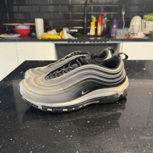 Nike air max 97 - 🎨 Färg: Svart / Grå / Silver 📏 Storlek: EU 42,5 / UK 8 / US 9 / CM 27 ♻️ Skick: Bra använt skick – vissa tecken på användning (se bilder) men fortfarande fräscha och i bra form. 🧵 Material: Mesh, syntet & gummi 📦 Skickas samma dag vid köp