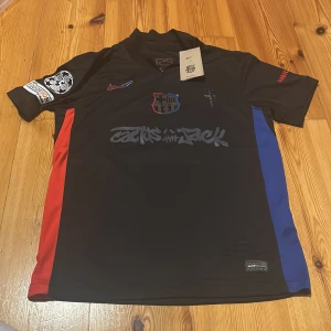 FC Barcelona x Nike Cactus Jack tröja - Säljer en svart FC Barcelona x Nike Cactus Jack fotbollströja i storlek S med röda och blå detaljer på sidorna. Tryck med Lamine Yamal 19 på ryggen och Cactus Jack-grafik på bröstet. Dri-FIT-material för bästa komfort. Unik collab med klubbmärke och specialpatchar. Säljer då ja köpt en extra. 