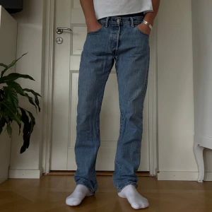 Levi's 501 ljusblå jeans straight fit - Klassiska Levi's 501 jeans i ljusblå denim med rak passform och normal midja, storlek W30 L32. Jeansen har knappgylf och den ikoniska läderpatchen bak i midjan. Dom är i bra skick men har två synliga slitningar, som visas på dom två sista bilderna. 