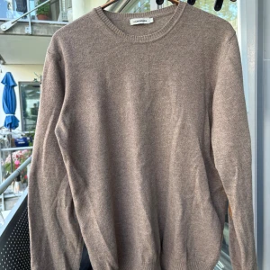 Brun stickad tröja J.Lindeberg s/m - Snygg brun stickad tröja från J.Lindeberg i ursprungsstorlek L som har krympt till mer av S/M. Tröjan har rund hals, ribbade muddar och coola mockadetaljer på armbågarna. Perfekt för dig som gillar en klassisk men ändå trendig look. Slitage i ändorna på ärmarna som säkert går att årgärda. 70% merino 30% Kashmir.