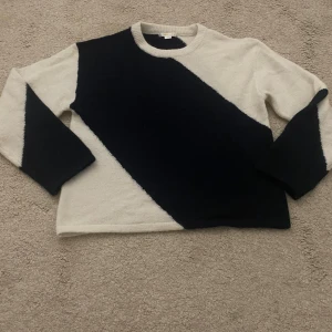 Blåvit stickad tröja Gina Tricot - Snygg stickad tröja från Gina Tricot i mörkblå och vitt med diagonal färgblock-design. Tröjan har rund halsringning och långa ärmar. Perfekt för dig som gillar en stilren men ändå unik look.