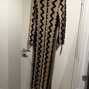Beige långklänning från NA-KD - Säljer en beige långklänning från NA-KD i storlek M. Klänningen har svarta vågiga ränder. Använt ett fåtal gånger, så gott som ny. Nypris 799kr