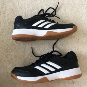 Svarta innegympaskor adidas - Snygga svarta Adidas sneakers med vita ränder på sidorna🤗Kan användas dagligen eller som gympaskor (både inne och ute)💎💕 ⚽️ strl: 36 2/3🌸 nästan oanvända och i mycket bra skick (nedsat använda inomhus) 🥰 ‼️pris kan diskuteras‼️