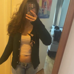 Mörkgrön kofta från Odd Molly med rosetter - Superfin mörkgrön kofta från Odd Molly med snygga knappar och tre rosa rosetter på framsidan. Koftan är stickad och har långärmade ärmar. 💓💞