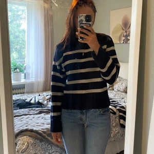 Randig marinblå stickad tröja - Säljer en stickad tröja i marinblått med breda vita ränder. Tröjan har en klassisk rund halsringning och långa ärmar. Den är lite loose i passformen och passar perfekt till jeans för en chill look.