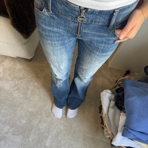 Blå bootcut jeans med dragkedja - Snygga blå jeans från Bik Bok med bootcut-modell och markerad dragkedja framtill. Jeansen har klassisk femficksdesign, låg midja och cool slitning längs benen. Perfekta för dig som gillar en retro vibe och vill ha ett par jeans som sticker ut.