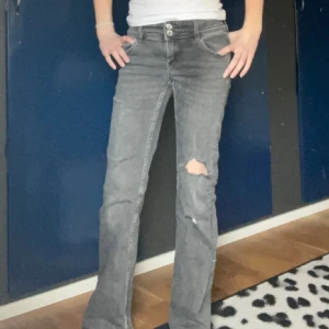 Grå bootcut jeans med slitningar - Säljer ett par grå jeans som är bootcut. Hålen har jag försökt att göra själv.