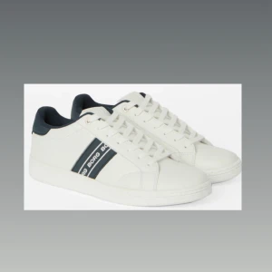 Vita sneakers från Björn Borg - Snygga vita sneakers från Björn Borg med marinblå detaljer och logga på sidan. Skorna har rund tå, platt sula och klassisk snörning. Tillverkade i syntetmaterial med mjuk insida och stilren design som passar till jeans eller shorts. Har endast använt dom 2 gånger men dom är inte min smak. 800kr eller bud. Kan även byta mot nåt som är intressant gör mig. Finns att hämta i Helsingborg eller frakt. Storlek 41. Kan fixas fler bilder vid intresse