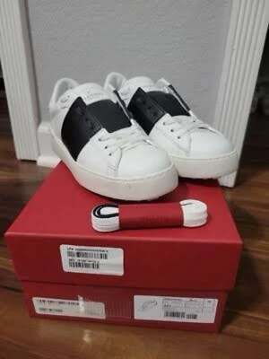 Valentino Garavani Open sneakers vit/svart - Säljer ett par Valentino Garavani Open sneakers i vitt skinn med bred svart rem över vristen. Klassisk låg modell med rund tå, vita snören och subtila nitar på hälen. Kommer med extra skosnören och originalkartong. Perfekta för dig som gillar lyxiga och stilrena sneakers.