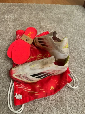 Adidas X Speedflow+ FG fotbollsskor - Ny pris är över 3000kr Säljer ett par Adidas X Speedflow+ FG fotbollsskor i vitt, svart och rött med gula detaljer. Skorna har en strömlinjeformad design utan snörning, lätta ovandelar i syntet och fasta dobbar för spel på naturgräs. Medföljer originalröda innersulor och matchande röd påse.