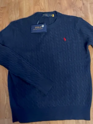 Ralph Lauren kabelstickad tröja navy - Polo Ralph Lauren kabelstickad tröja i mörkblått. Klassisk design med röd logga på bröstet. Superclean och lätt att styla, funkar perfekt till vardag eller mer dressad look. Tags kvar. Kan alltid gå ner i pris😁