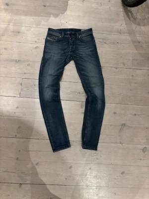 Diesel jeans blå W29 - Säljer ett par snygga blå Diesel jeans i  fit. Jeansen har klassisk femficksdesign, smal passform och stretchigt denimtyg. Färgen är mörkblå med slitningar och tvättade detaljer för en cool look. Perfekta till sneakers eller boots.