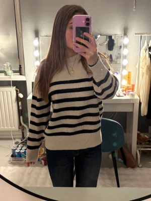 Randig stickad tröja från H&M - Mysig stickad tröja från H&M i beige med svarta ränder. Tröjan har rund hals, ribbade muddar och är långärmad. Väldigt varm så passar kalla dagar och för någon som fryser lätt ❣️