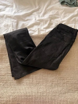 Svarta high waist jeans från 157 - Säljer ett par svarta jeans från 157 med hög midja och klassisk femficksmodell. Jeansen har raka ben och silverfärgade nitar vid fickorna. Materialet är mjukt och stretchigt, vilket gör dem riktigt sköna att bära.