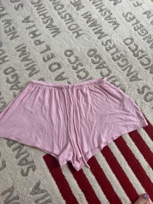 Ljusrosa shorts från Gina Tricot - Säljer ett par ljusrosa shorts från Gina Tricot. De har en avslappnad passform med resår i midjan och är gjorda i mjuk bomull. Perfekta för chill dagar eller som mysplagg hemma.