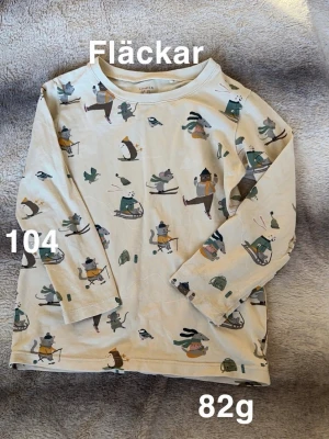  långärmad t-shirt Lindex barn - Söt långärmad t-shirt från Lindex med gulligt vintermönster av djur som åker skidor, skridskor och pulka. perfekt för mysiga dagar. Motiv i grönt, brunt och gult ger en lekfull känsla.🌸 Fläckar. Storlek 104