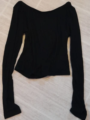Svart topp med öppen rygg - Säljer en svart topp från SHEIN med öppen rygg i storlek S. Toppen har långa ärmar och en tight passform. Tillverkad i mjukt material som känns skönt mot huden. Perfekt att styla med jeans eller kjol för en trendig look.  !!endast swish +frakt!!