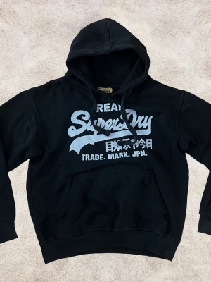 Superdry hoodie XS - En snygg hoodie från Superdry i färgen svart med ljusgrått tryck. Storlek XS-S. Bra skick. 😀