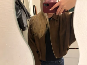 Brun mocka bomberjacka - Säljer en brun bomberjacka i mjuk mocka-look med dragkedja framtill. Använt ett fåtal gånger. Jackan har en loose passform. Perfekt för dig som vill ha en chill och trendig vibe till din outfit. Den är i storlek M men passar den med storlek S. 
