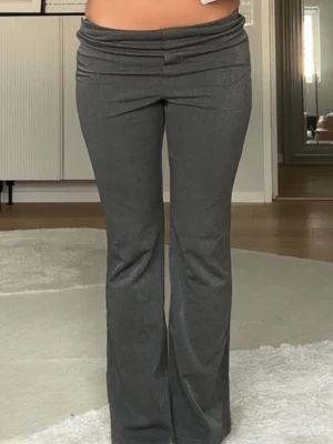 Grå lågmidjade kostymbyxor från Zara  - Säljer ett par grå kostymbyxor med låg midja  som är bootcut. Byxorna har en snygg omlottdetalj i midjan och är gjorda i ett mjukt, vävt material som ger en clean look. Perfekta för dig som gillar trendiga siluetter och vill ha något som sticker ut. Priset är ej satt så vid snabba köp kan de prutas ned. Kontakta vid frågor ❤️