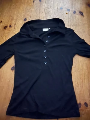 Svart ribbad topp från Nelly - Säljer en svart ribbad topp från Nelly i storlek S. Toppen har krage och knappar framtill Perfekt till jeans eller kjol för en clean look. Köpt på Nelly nån gång under förra året men ej kommit till användning och har nu blivit för liten. (Kan tyvärr inte skcika bild på då den som sagt är för liten)❤️