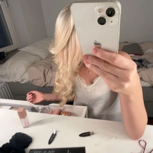 Vit spetskantad linnetopp - Säljer en söt vit linnetopp med tunna axelband och vacker spetskant vid urringningen. Toppen är ärmlös och har en lätt, luftig känsla som passar perfekt till varma dagar. Enkel och stilren design som är lätt att matcha.