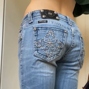 Low waist bootcut miss me jeans - Snygga lågmidjade jeans från Miss Me i modellen ”boot” med broderade bakfickor och blingdetaljer. Defekter finns på näst sista bilden. Jeansen har även hål med skosnören i midjebandet då de varit lite stora för mig! Men de är inget som syns när man har på sig och de går alltid att ta bort🤗🤗