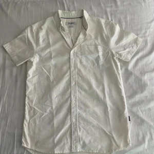 Vit kortärmad skjorta från Strömberg - Säljer en stilren vit skjorta från Strömberg i bomull. Skjortan har korta ärmar, klassisk krage, bröstficka och knäppning framtill. 