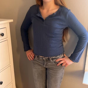 Mörkblå ribbad topp från lager 157 - Mörkblå långärmad topp från 157 i ribbad bomull med knappar framtill. Modellen är croppad med vågig kant nertill och vid ärmslut. Enkel och stilren design som passar till de mesta! Aldrig använd!!