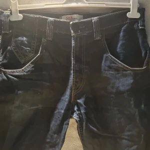 Levi's 503 Loose jeans mörkblå - Mörkblå Levi's 503 Loose jeans med kontrastsömmar och klassiska fem fickor. Byxorna har bred passform och raka ben, samt snygga detaljer på bakfickorna med knappar. Perfekta för dig som gillar en avslappnad stil.