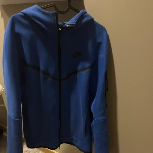 Blå Nike hoodie med dragkedja - Snygg blå hoodie från Nike tech fleeze. Köpt för runt 1000kr. Skick 9/10 väldigt sparsamt använd och mycket bra skick. Skriv gärna vid frågor och annat Mvh